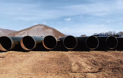 Row of pipes on field against sky