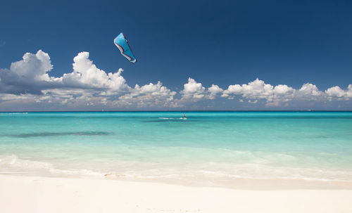 Kitesurfer with kiteboard in front of an amazing and deserted tropical beach