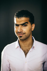 Portrait of young man against black background