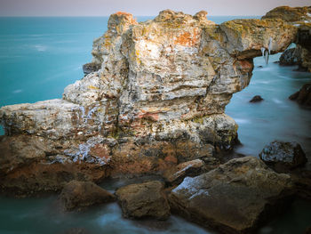 Rock formation on beach against sky