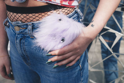 Midsection of young woman keeping mobile phone in jeans pocket