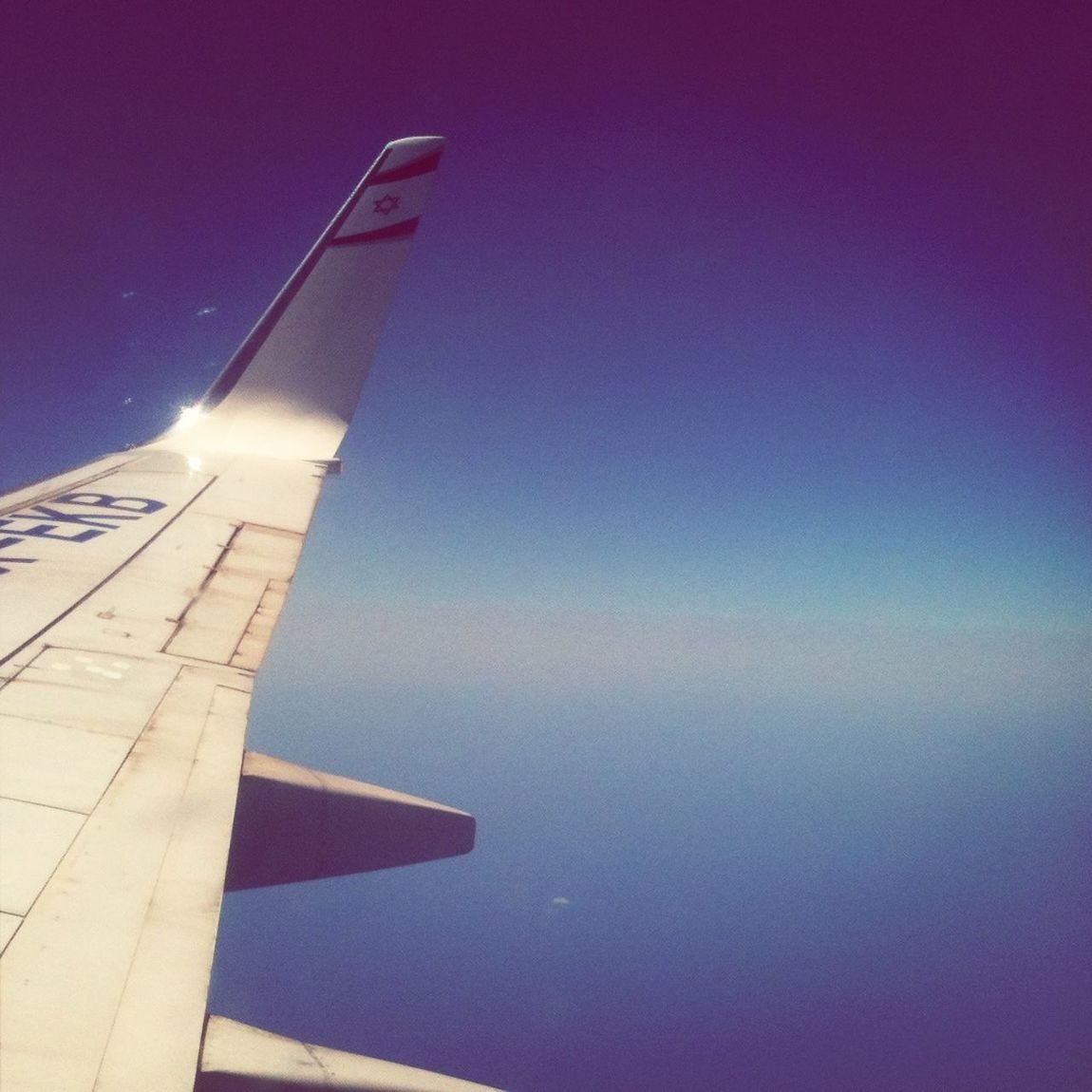 airplane, air vehicle, low angle view, transportation, flying, aircraft wing, mode of transport, part of, blue, clear sky, mid-air, cropped, sky, copy space, no people, sunlight, vapor trail, travel, outdoors, journey