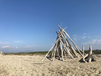 Wooden structure on beach against blue sky