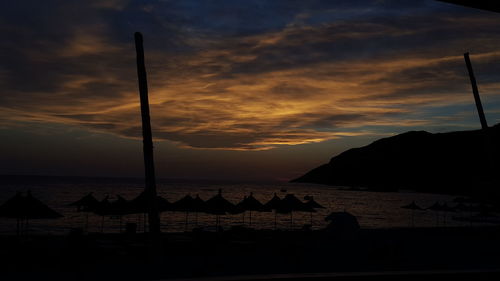 Silhouette people on beach against sky during sunset