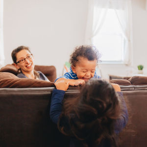 Siblings playing by mother at home