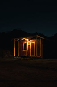 A warm-lit red hut creates a tranquil scene at night. ideal for travel and nordic showcases.