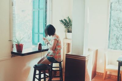 Woman sitting on chair at window