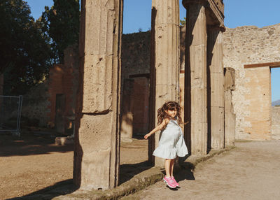 Rear view of girl  standing between ruins in pompei