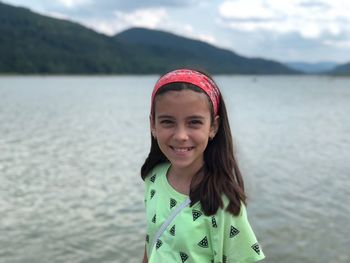 Portrait of smiling woman standing against lake