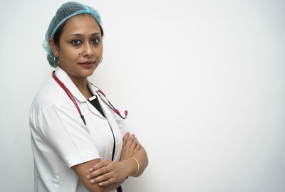 Portrait of young woman standing against white background