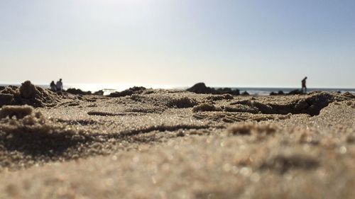Surface level of sand on beach against clear sky