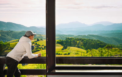 Rear view of man looking at landscape against sky