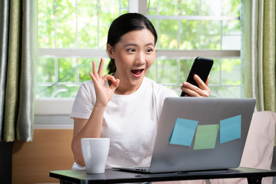 Young woman using mobile phone at table