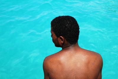 Rear view of shirtless man swimming in pool