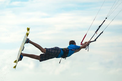 Low angle view of man paragliding against sky