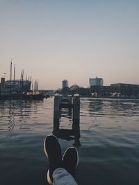 Low section of person in sea against clear sky