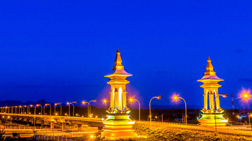 Illuminated city against blue sky at night