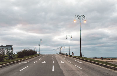 Vehicles on road against cloudy sky