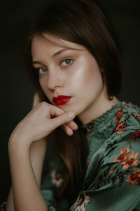 Close-up portrait of beautiful young woman against black background