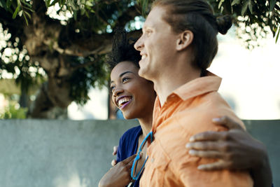 Smiling couple with arms around walking against building