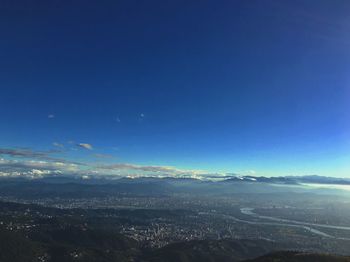 Aerial view of landscape and sea against blue sky