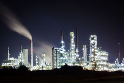 Illuminated petrochemical plant against sky at night