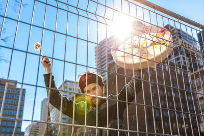 Low angle view of metal in cage against building on sunny day