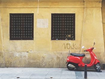 Red motor scooter against yellow wall