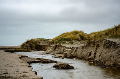 Scenic view of rocks by sea against sky