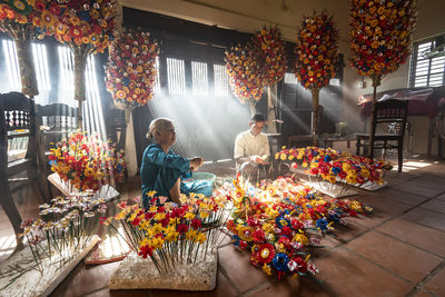 People standing by flowering plants at market stall