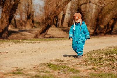 Full length of boy walking on dirt road