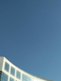 Low angle view of balloons against building against clear blue sky