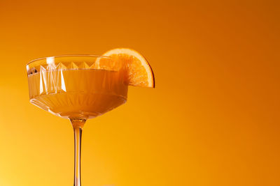 Close-up of champagne flute against yellow background