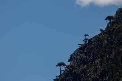 Low angle view of cliff against clear blue sky