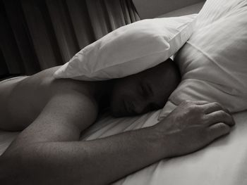 Portrait of shirtless man relaxing on bed at home