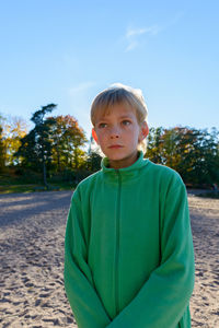 Portrait of boy standing against sky