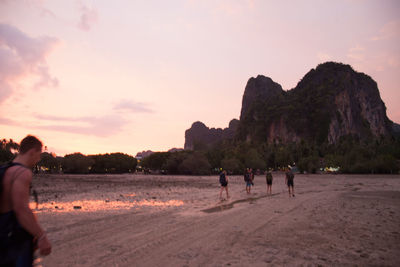 Tourists on rock formation at sunset