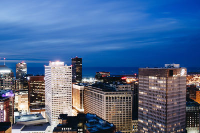 Illuminated cityscape against blue sky