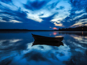 Boat moored in lake against sky during sunset