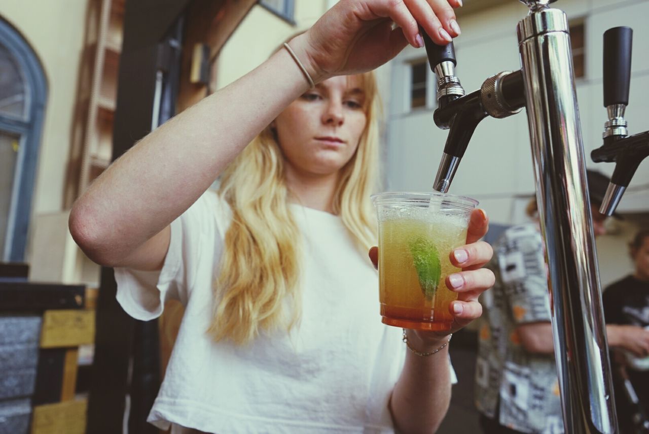 CLOSE-UP OF WOMAN HOLDING BEER