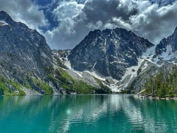 Scenic view of lake in front of snowcapped mountains against sky