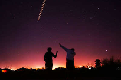 Silhouette people standing against sky at night