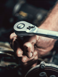 Cropped hands of mechanic repairing engine of car