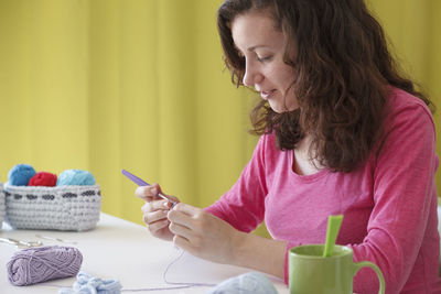 Midsection of woman holding while sitting on table at home