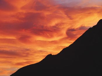 Low angle view of silhouette mountains against orange sky