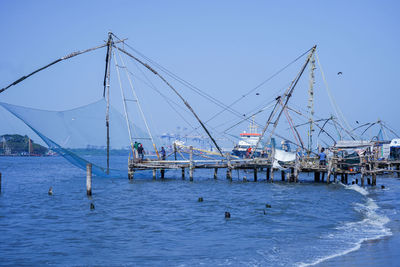 Fishing boats in sea against clear blue sky