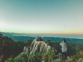 Rear view of woman standing on mountain against sky