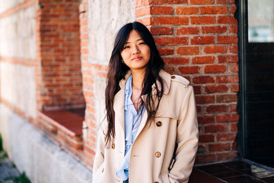 Portrait of woman standing against wall