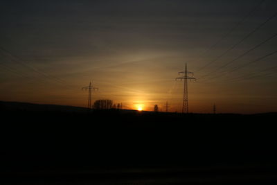 Silhouette electricity pylon against sky during sunset