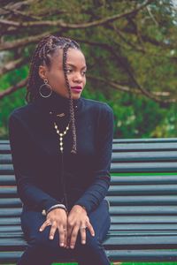 Young woman looking away while sitting outdoors